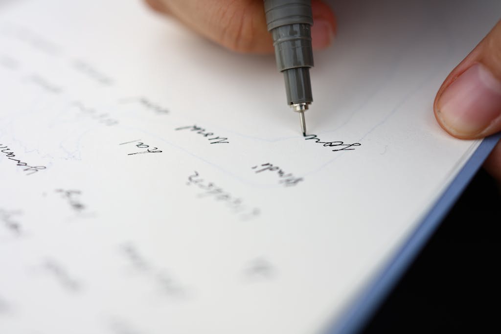 Close-up of a hand writing on paper with a pen, showcasing detail.